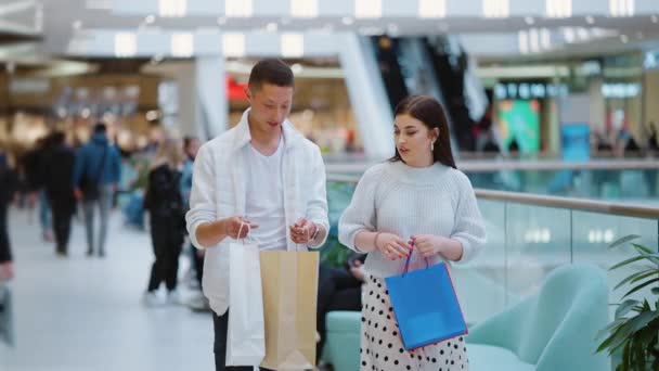 Pareja joven caminando con bolsas de compras en el centro comercial — Vídeos de Stock