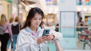 Asyalı kadın telefonda mesaj atıyor.