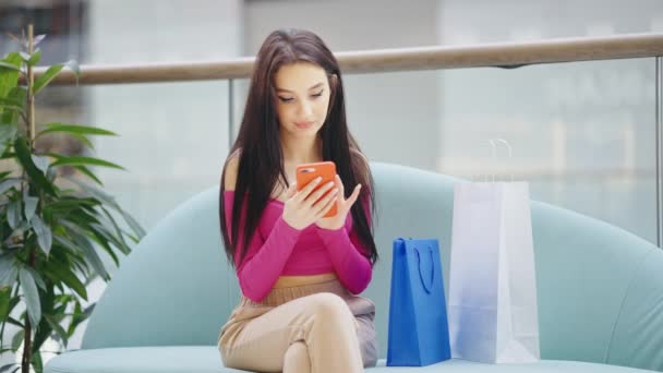Веселая женщина разговаривает по телефону в торговом центре — стоковое видео