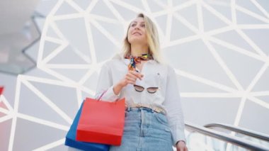 Alışveriş merkezinde merdivenlerde yürüyen bir kadın.