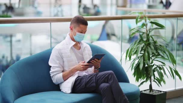 Hombre con máscara leyendo e-book en el centro comercial — Vídeos de Stock