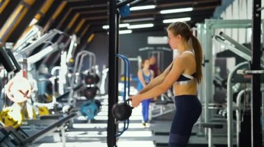 Fit kadın ağır çekimde kettlebell ile çalışıyor.
