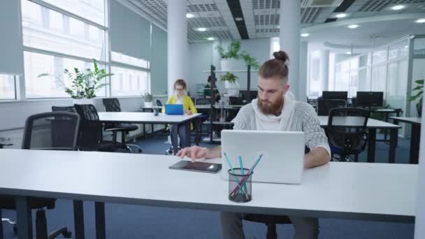 Hipsterski biznesmen korzystający z laptopa i tabletu w biurze — Wideo stockowe