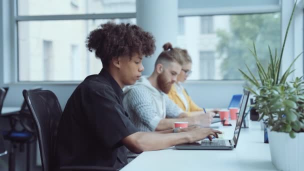 Чернокожий мужчина работает на ноутбуке в офисе — стоковое видео