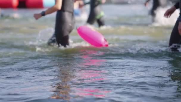 Zeitlupenmenschen in Neoprenanzügen laufen im Wasser — Stockvideo