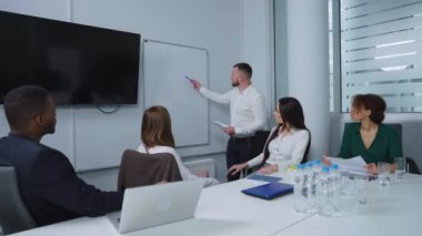 Proje yöneticisi flipchart yakınlarındaki iş akışı hakkında rapor veriyor