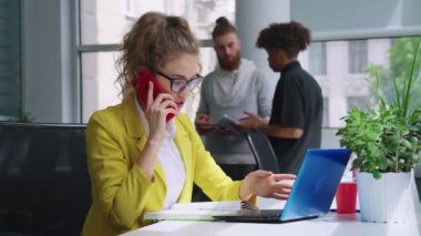 İş kadını iş yerinde telefonda konuşuyor.