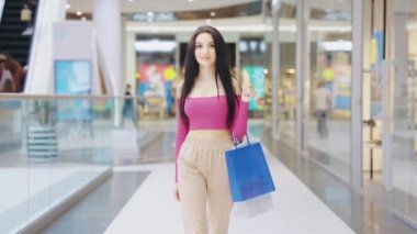 Alışveriş merkezinde ağır çekimde yürüyen kadın.