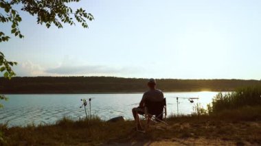 Nehir kenarında oturan ve bira içen balıkçı.