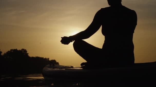 Woman doing yoga on SUP board at sunset — Stock Video
