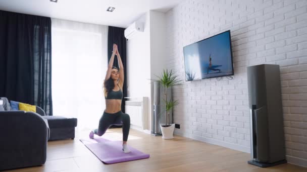 Fit vrouw kijken video en het doen van yoga thuis — Stockvideo