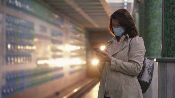 Woman using smartphone on subway platform — Stock Video