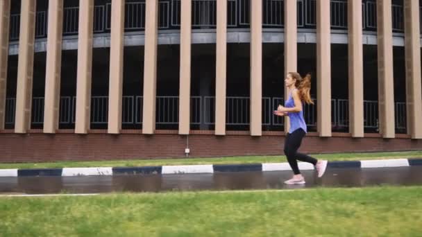 Frau joggt in Zeitlupe gegen Gebäude — Stockvideo