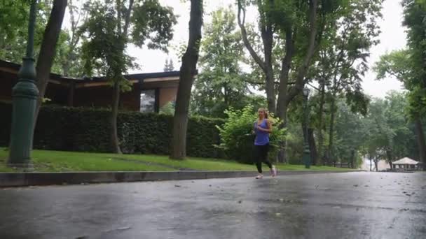 Женщина бегает в парке после дождя — стоковое видео