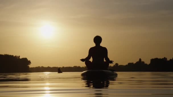 SUP boarder fazendo ioga ao pôr do sol — Vídeo de Stock