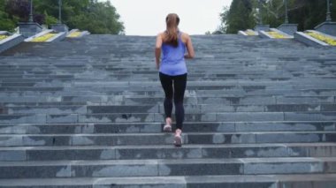 Kadın merdivenlerde ağır çekimde koşuyor.