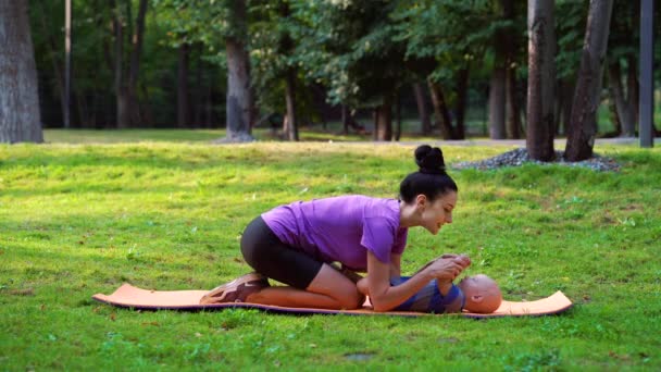 Moeder zoenen baby op yoga mat in park — Stockvideo