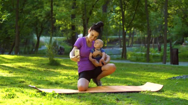 女性レコーディングビデオとともに赤ん坊で公園 — ストック動画