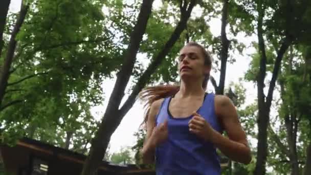Corrida feminina em câmera lenta correndo sob árvores — Vídeo de Stock