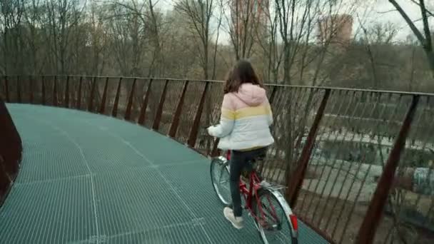 Медленно двигающаяся девушка на велосипеде по мосту — стоковое видео