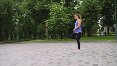 Parkta koşmadan önce bacaklarını esneten sağlıklı bir kadın.