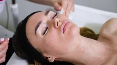 Kozmetik uzmanının elleri kadın yüzünden maskeyi çıkarıyor.