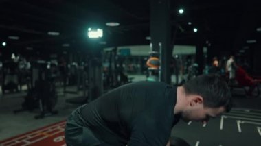 Spor salonunda halterle egzersiz yapan kaslı bir adam.
