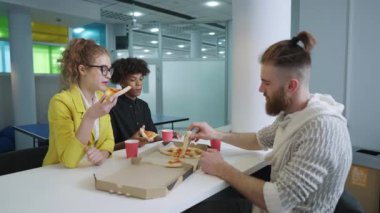 Öğle arasında pizza yiyen çok ırklı arkadaşlar.