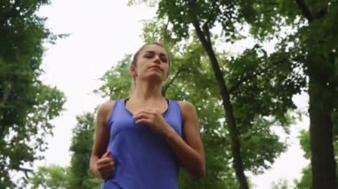 Kadın koşucu yavaş çekimde ağaçların altında koşuyor