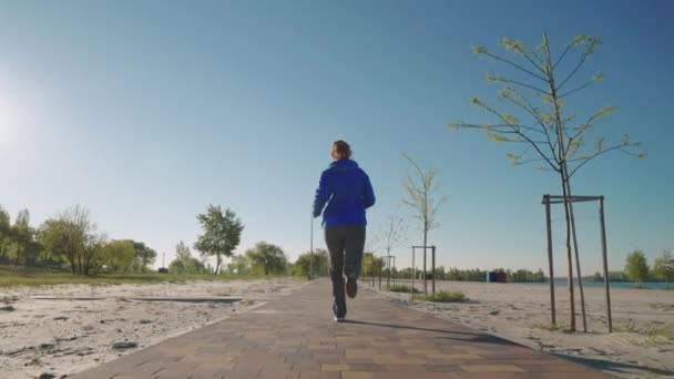 Vrouw joggen door het strand in slow motion — Stockvideo