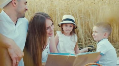 Anne aile pikniğinde çocuklara komik kitaplar okuyor.