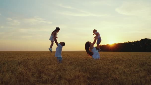 Pais jogando crianças no ar no campo — Vídeo de Stock
