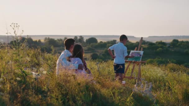 Jongensschilderij op doek in de natuur — Stockvideo