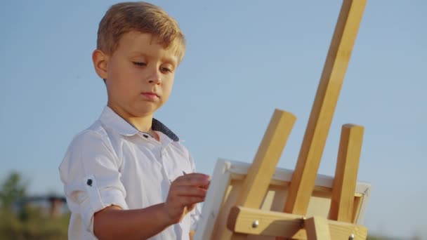 Little boy drawing on canvas outside — 图库视频影像