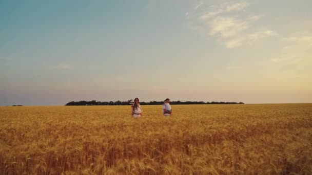 Mamma e papà che trasportano bambini in armi in campo — Video Stock