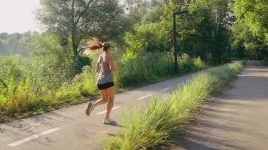 Ağır çekim kadın sabah parkta koşuyor.
