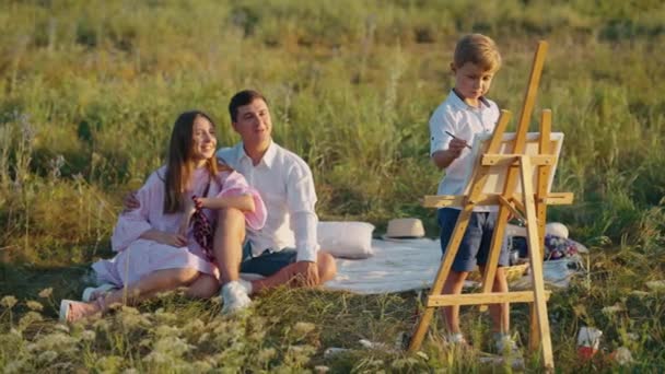 Liten pojke konstnär ritar i det fria på familj picknick — Stockvideo