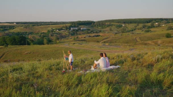 Famille relaxante sur prairie et enfant peinture sur toile — Video