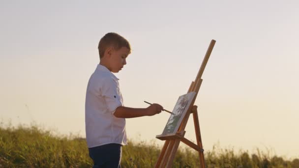Chłopiec rysunek na płótnie na świeżym powietrzu — Wideo stockowe