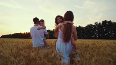 Ağır çekimde çocuklar kucağında sahada yürüyen aileler.