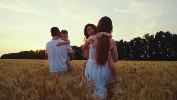 Lassan mozgó szülők sétálnak a mezőn a gyerekekkel a karjaikban — Stock videók