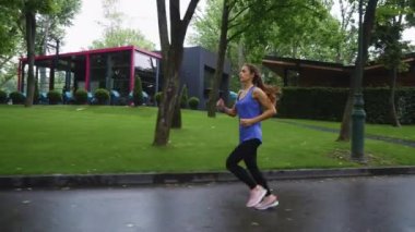 Sağlıklı kadın yağmurdan sonra parkta koşuyor.