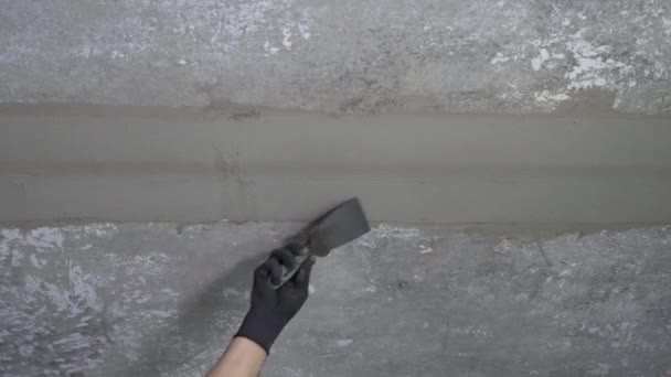 Hand of builder removing putty from ceiling — Stock Video