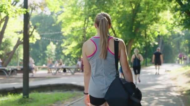 Повільний рух спортивної жінки, що перевозить сумку в парку — стокове відео