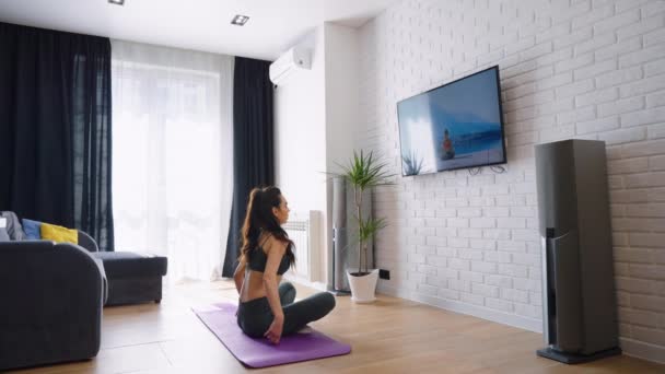 Kobieta oglądająca kurs jogi i siedząca w pozycji lotosu — Wideo stockowe