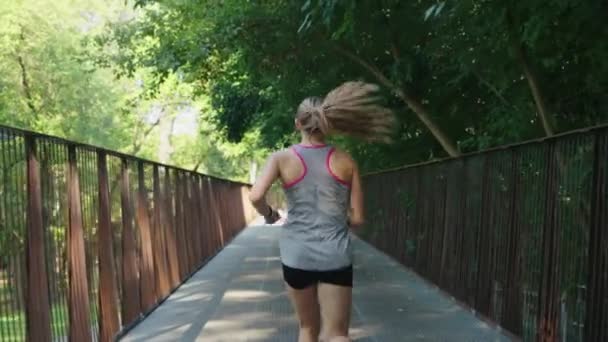 スローモーションフィット女性ジョギングオンブリッジ — ストック動画