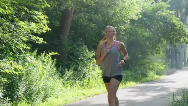 Lassú mozgás szőke nő kocog a parkban — Stock videók