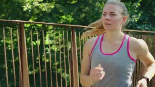 Blonde Frau joggt in Zeitlupe auf Brücke — Stockvideo