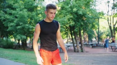 Atletik adam parkta koşmadan önce egzersiz yapıyor.