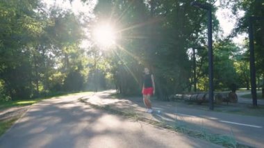 Yavaş çekim adamı güneşli parkta zıplıyor.